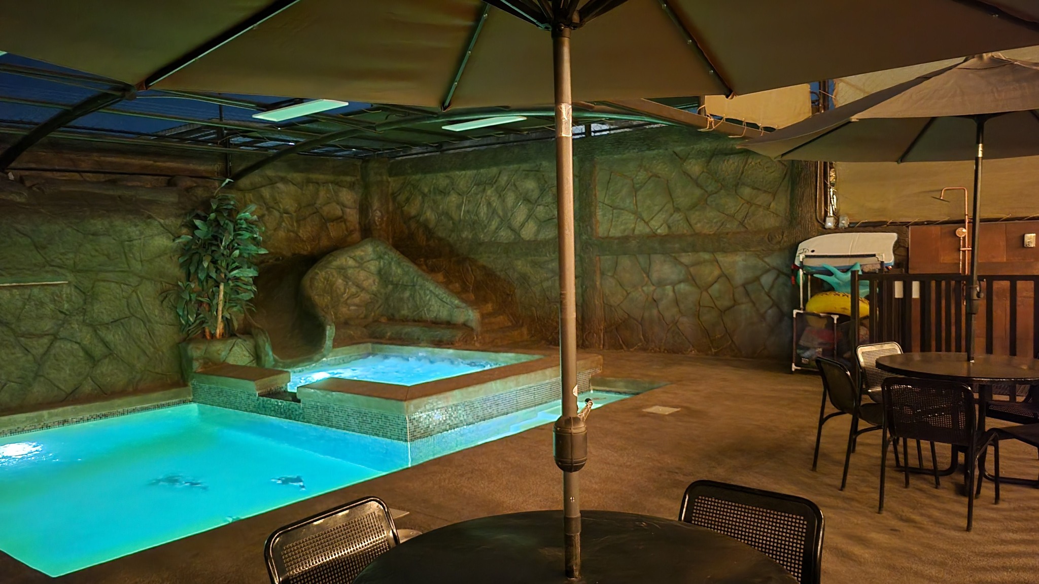 Alberca iluminada de noche con estructura de sombra