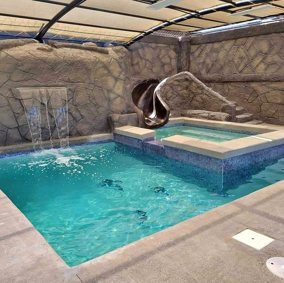 Alberca con resbaladilla, cascada y estructura de sombra en Jardin Plumerias