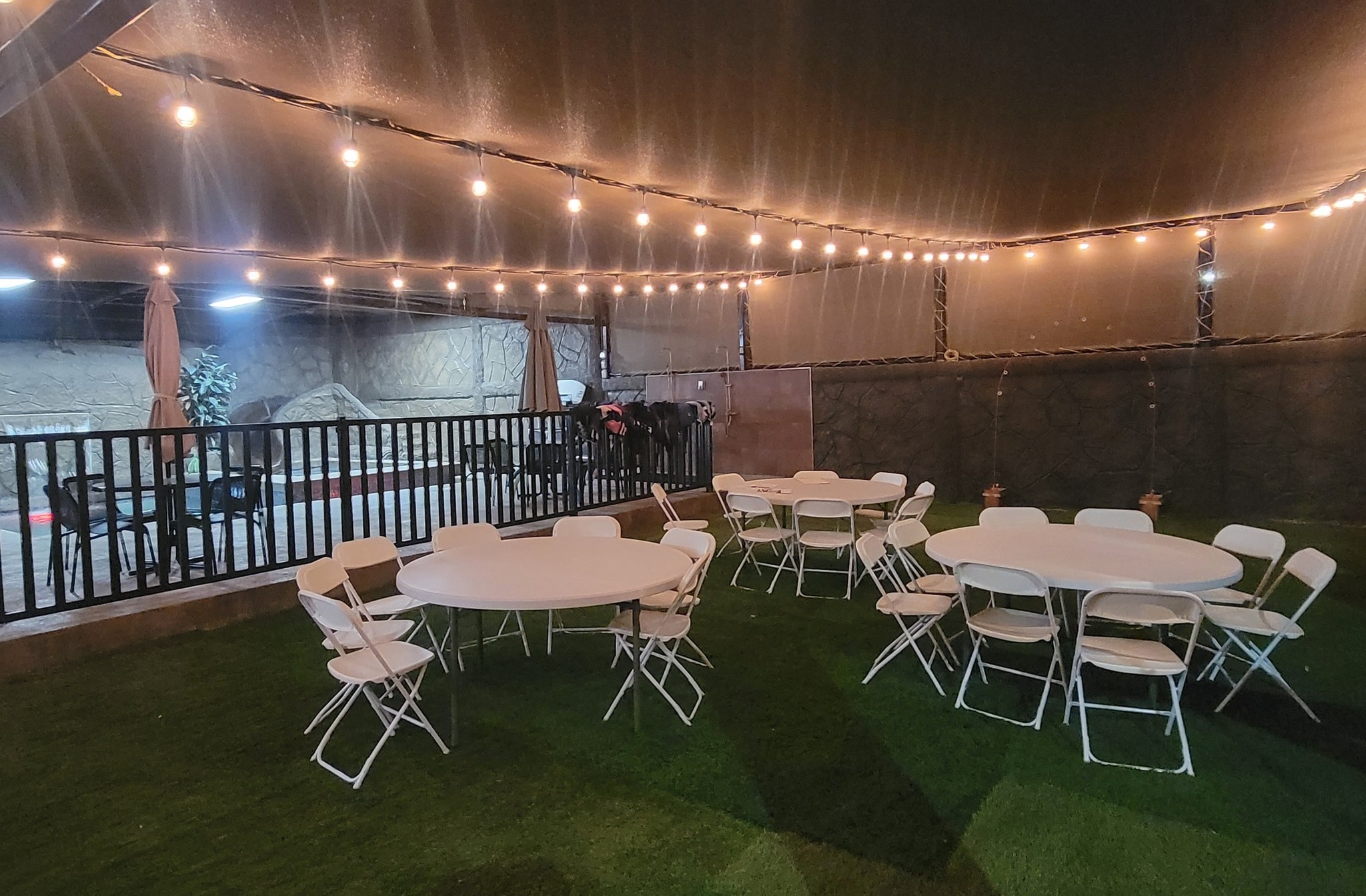 Jardín con mesas y luces cálidas de noche